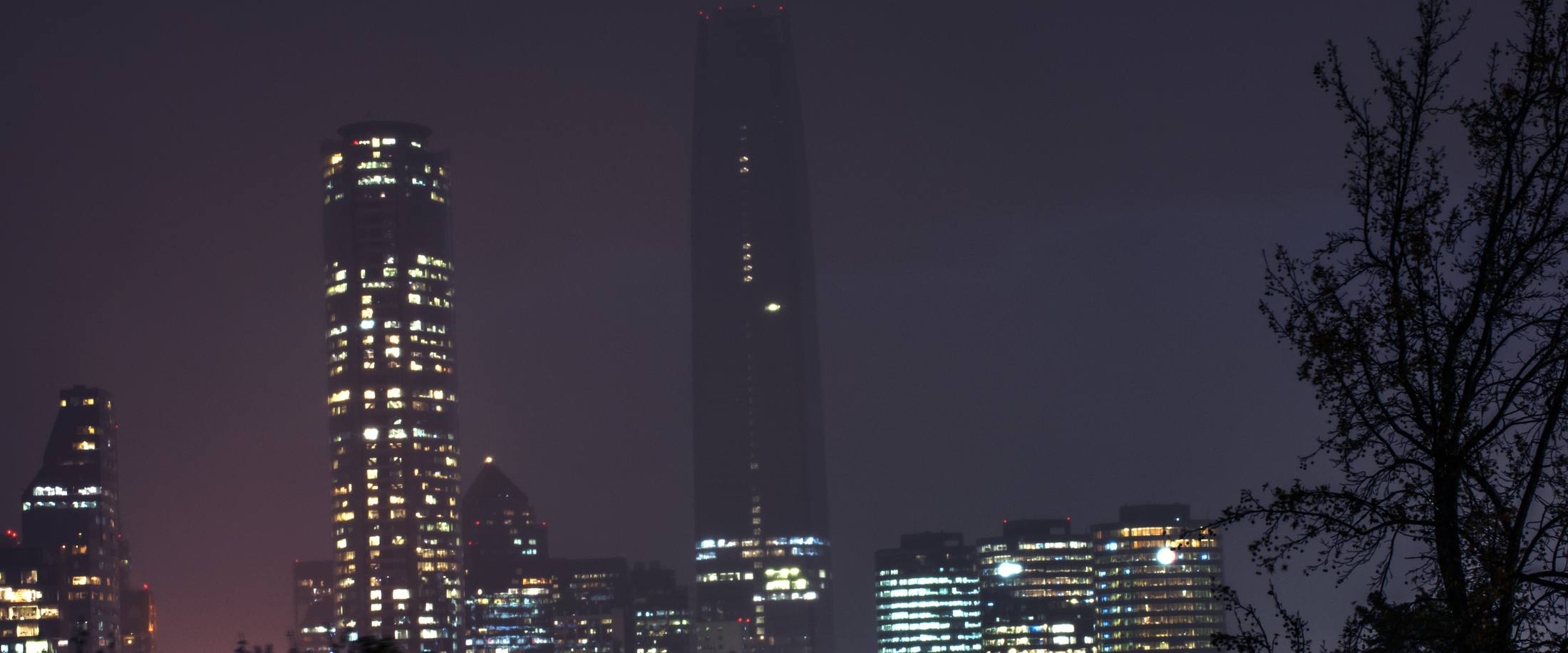 Night skyline of the Sanhattan financial district with its lit towers and the Gran Torre Santiago in silhouette